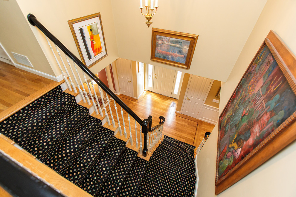 Идея дизайна: угловая лестница среднего размера с ступенями с ковровым покрытием, ковровыми подступенками и деревянными перилами