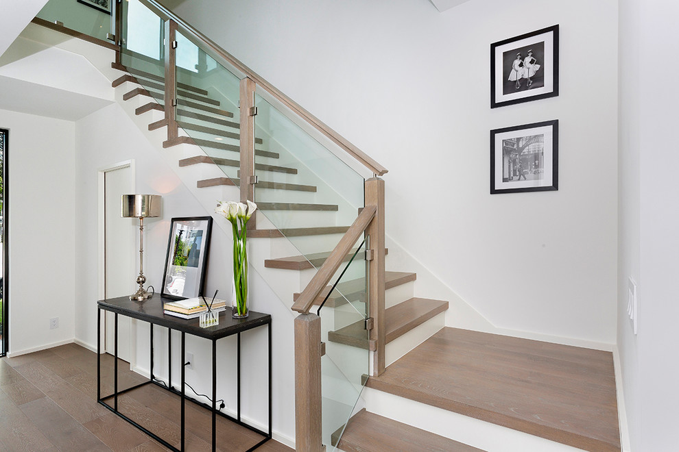 Exemple d'un escalier moderne en U de taille moyenne avec des marches en bois, des contremarches en verre, un garde-corps en bois et éclairage.