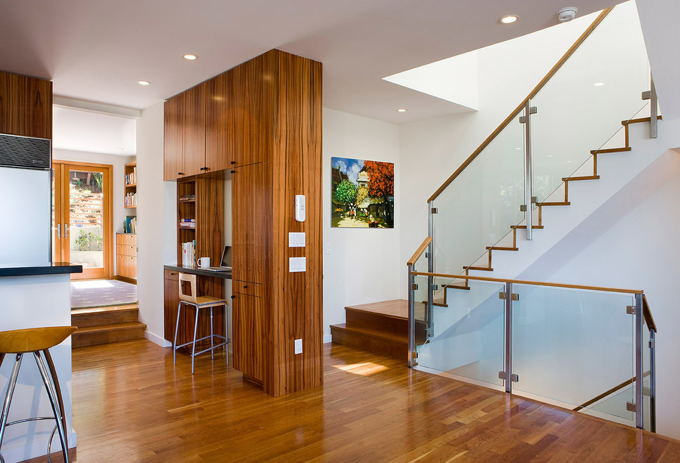 Idée de décoration pour un escalier design avec des marches en bois, des contremarches en bois et un garde-corps en verre.