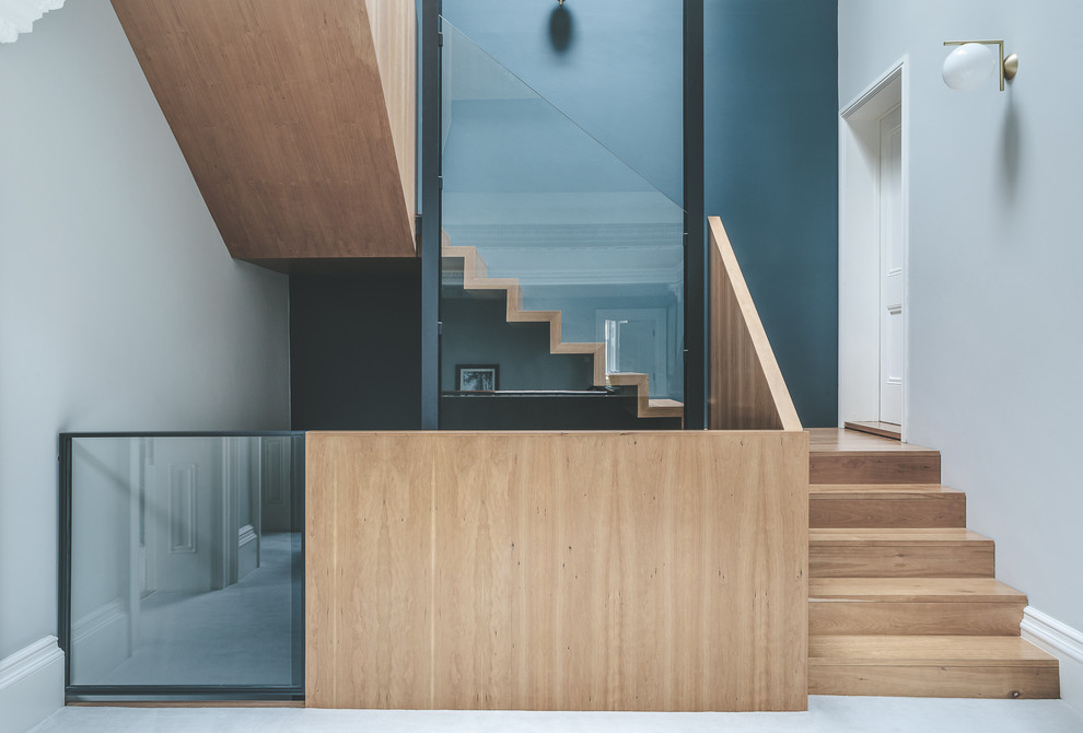 Contemporary wood u-shaped glass railing staircase in Other with wood risers.