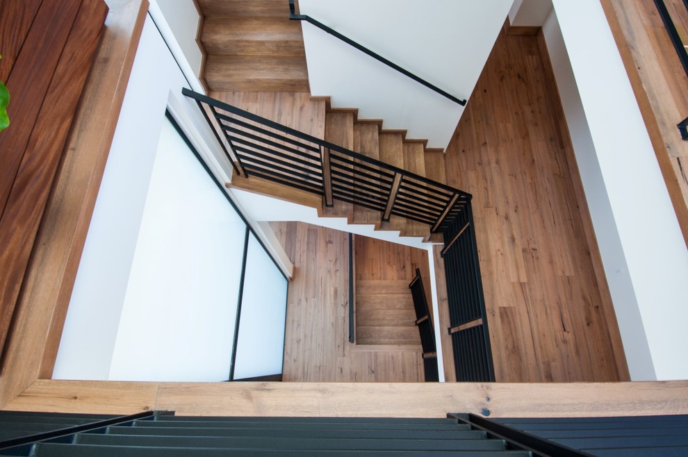 Aménagement d'un grand escalier moderne en L avec des marches en bois et des contremarches en bois.