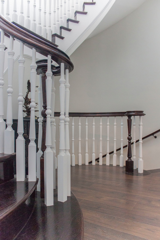 Imagen de escalera de caracol clásica renovada grande con escalones de madera, contrahuellas de madera y barandilla de madera
