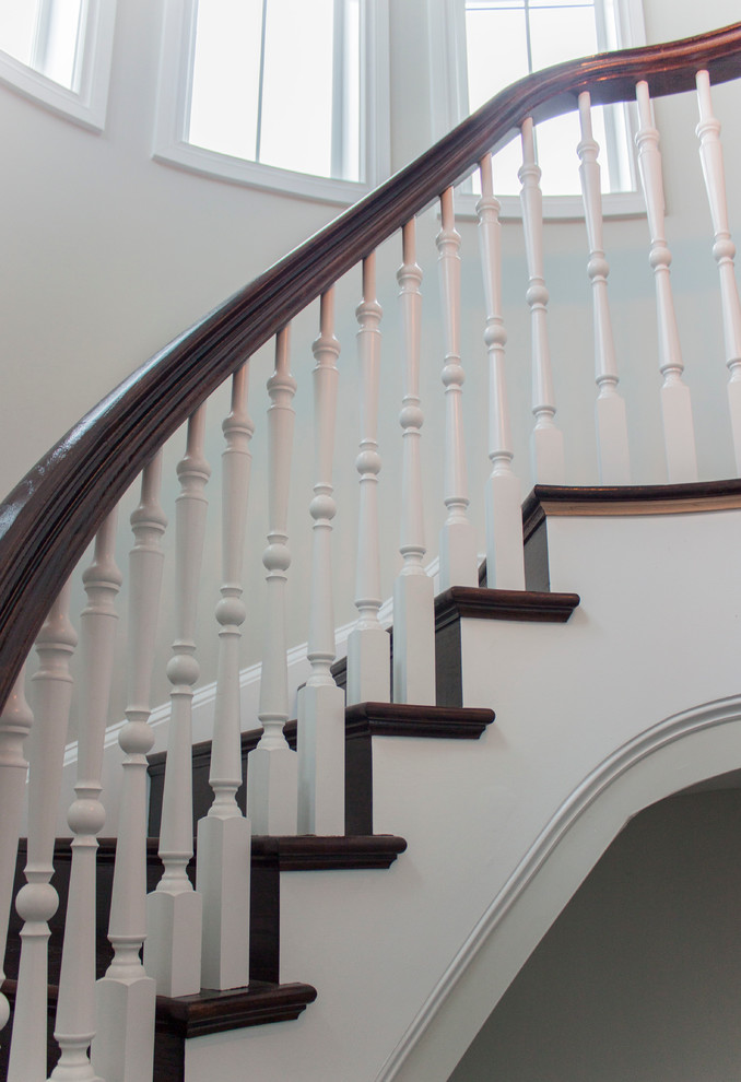 Photo of a large classic wood spiral wood railing staircase in DC Metro with wood risers.
