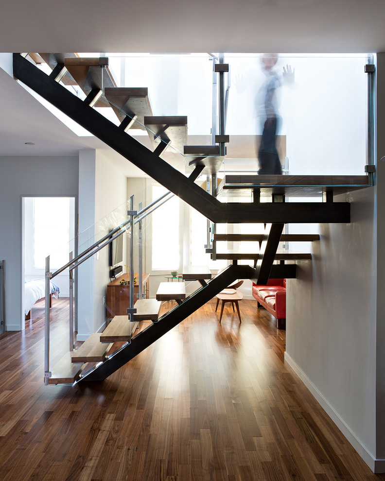 Modelo de escalera suspendida minimalista grande sin contrahuella con escalones de madera y barandilla de vidrio