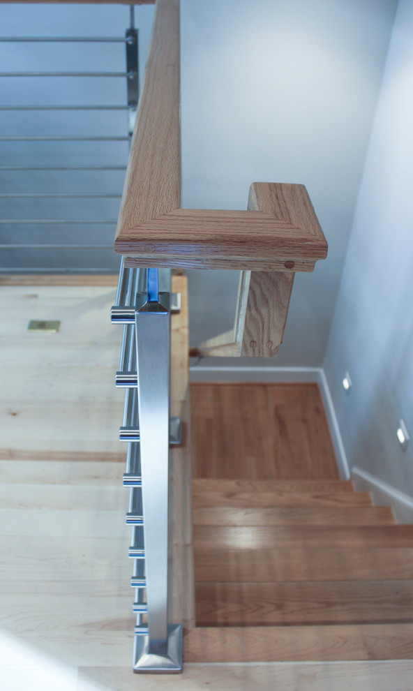 Exempel på en mellanstor modern rak trappa i trä, med sättsteg i trä och räcke i flera material