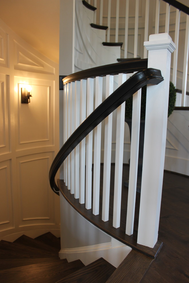 На фото: огромная изогнутая деревянная лестница в стиле фьюжн с деревянными ступенями и деревянными перилами