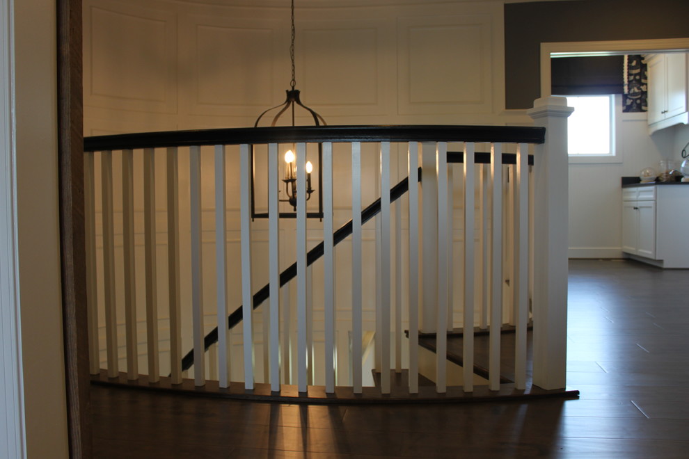 Immagine di un'ampia scala curva eclettica con pedata in legno, alzata in legno e parapetto in legno