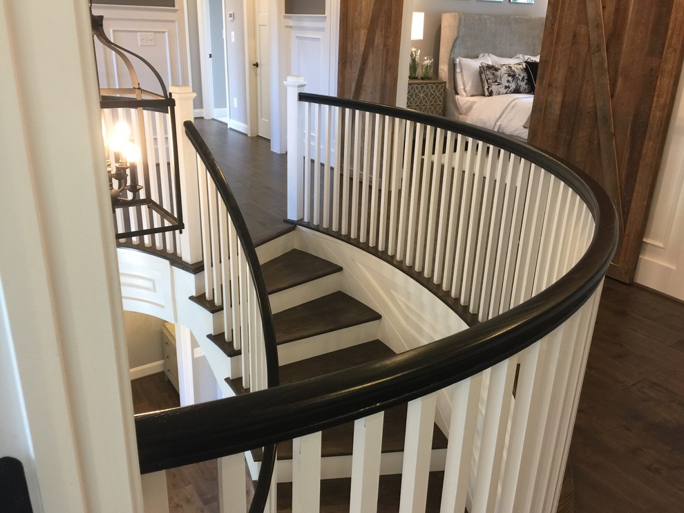 Ejemplo de escalera curva bohemia extra grande con escalones de madera, contrahuellas de madera y barandilla de madera