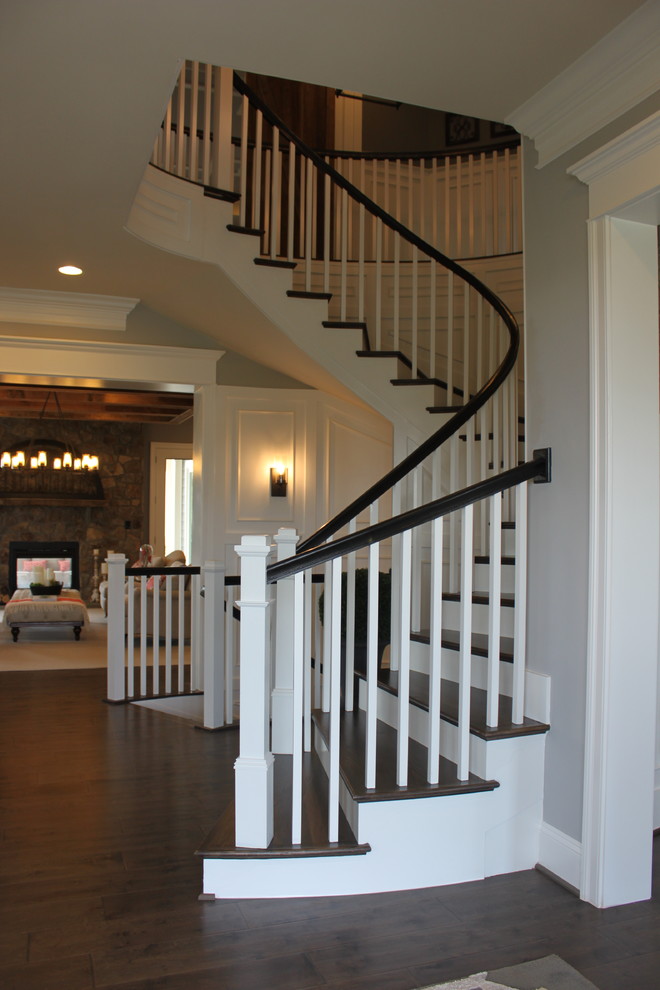 Idée de décoration pour un très grand escalier courbe bohème avec des marches en bois, des contremarches en bois et un garde-corps en bois.
