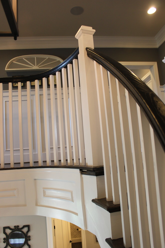 Aménagement d'un très grand escalier courbe éclectique avec des marches en bois, des contremarches en bois et un garde-corps en bois.