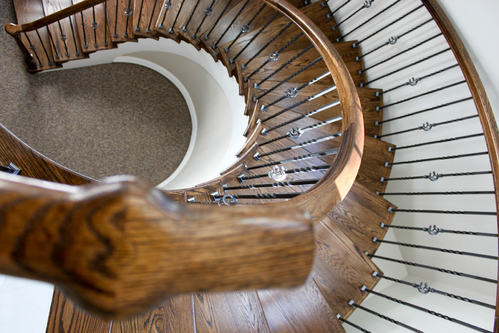 Imagen de escalera de caracol clásica extra grande con escalones de madera, contrahuellas de madera y barandilla de varios materiales