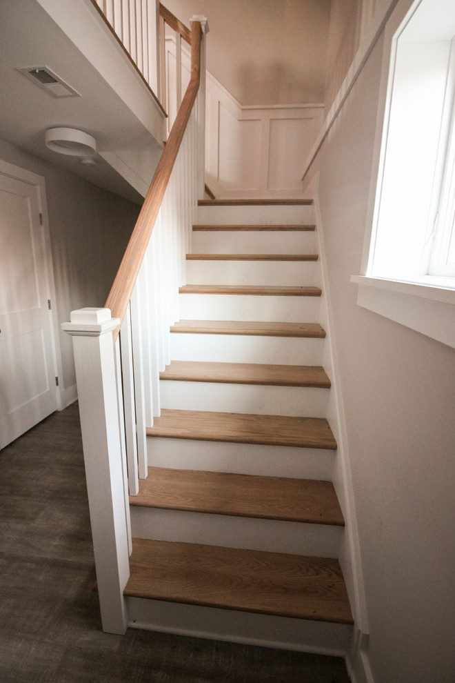 На фото: большая угловая деревянная лестница в стиле шебби-шик с деревянными ступенями и деревянными перилами с