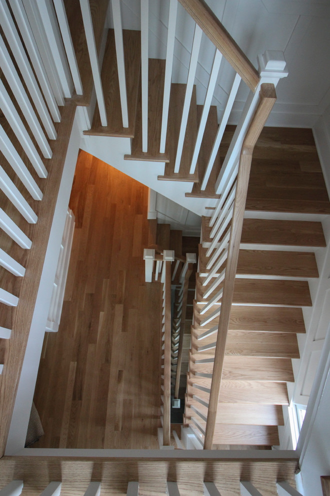 На фото: большая угловая деревянная лестница в стиле шебби-шик с деревянными ступенями и деревянными перилами