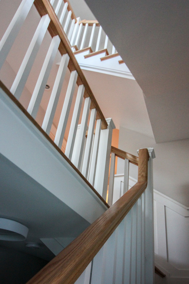Cette image montre un grand escalier style shabby chic en L avec des contremarches en bois, des marches en bois et un garde-corps en bois.