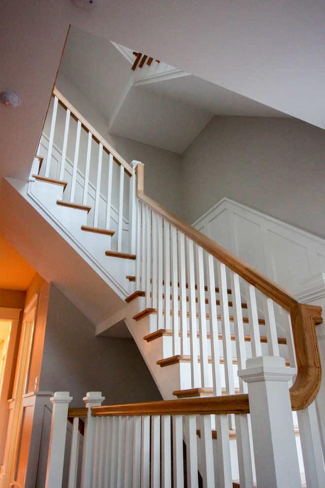 Diseño de escalera en L romántica grande con contrahuellas de madera, escalones de madera y barandilla de madera