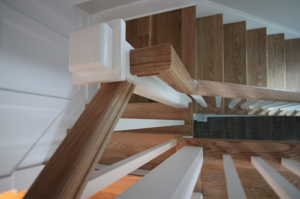 Cette image montre un grand escalier style shabby chic en L avec des contremarches en bois, des marches en bois et un garde-corps en bois.