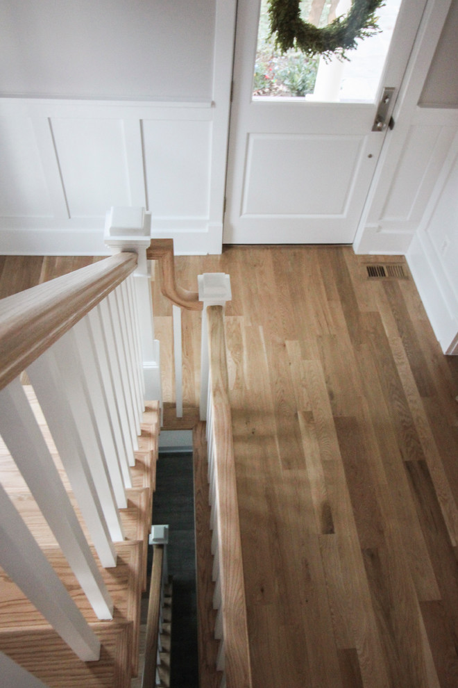 Diseño de escalera en L romántica grande con contrahuellas de madera, escalones de madera y barandilla de madera