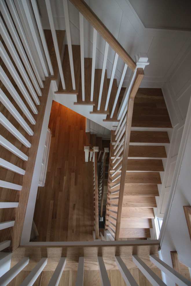 Modelo de escalera en L romántica grande con contrahuellas de madera, escalones de madera y barandilla de madera