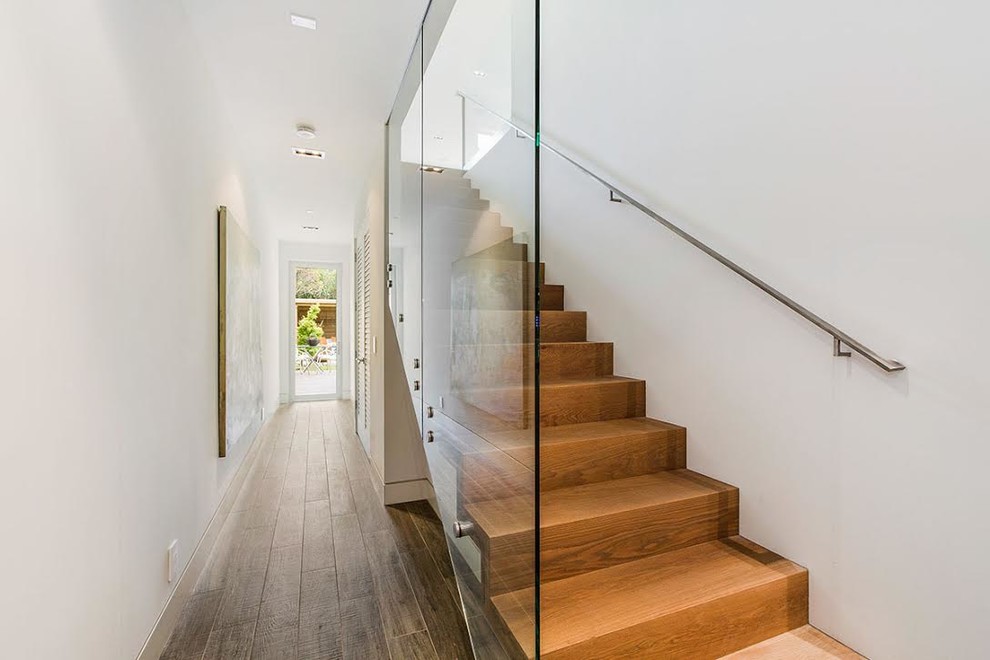 Свежая идея для дизайна: прямая деревянная лестница среднего размера в стиле модернизм с деревянными ступенями и стеклянными перилами - отличное фото интерьера