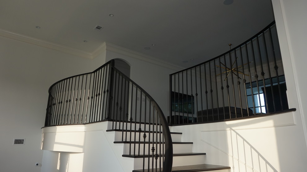 Imagen de escalera curva contemporánea grande con escalones de madera, contrahuellas de madera pintada y barandilla de metal