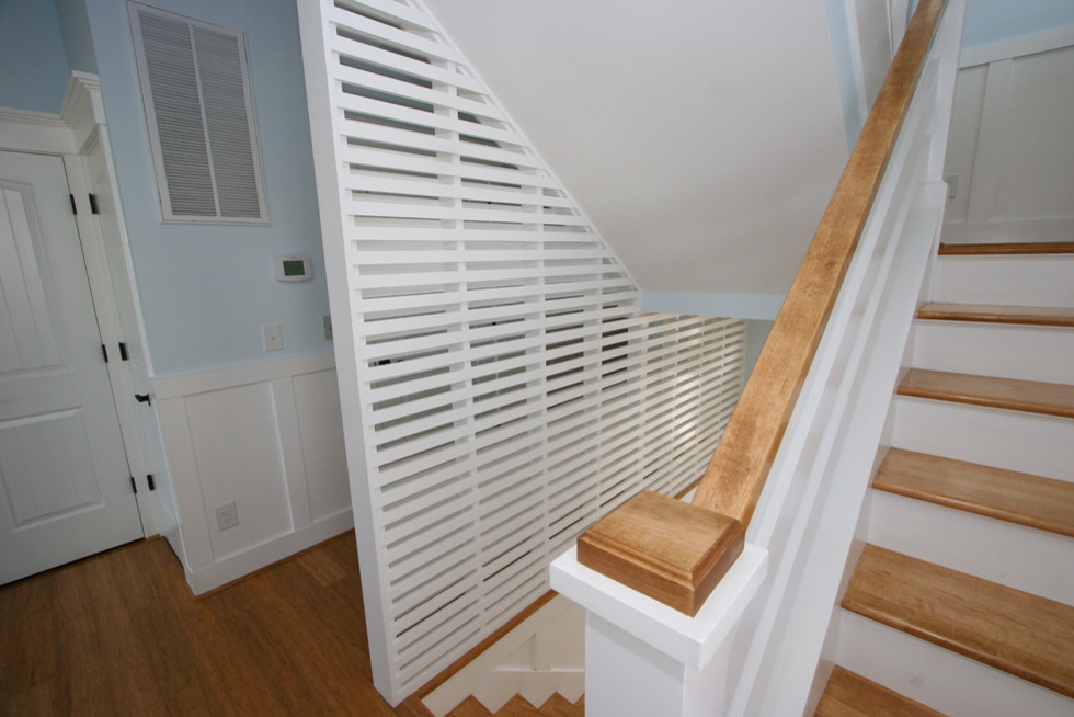 На фото: п-образная лестница среднего размера в морском стиле с деревянными ступенями и крашенными деревянными подступенками