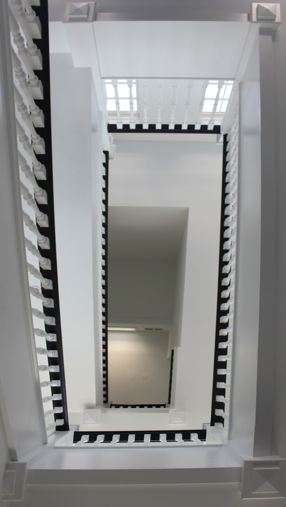 ワシントンD.C.にあるラグジュアリーな巨大なトランジショナルスタイルのおしゃれな折り返し階段 (木の蹴込み板、木材の手すり) の写真