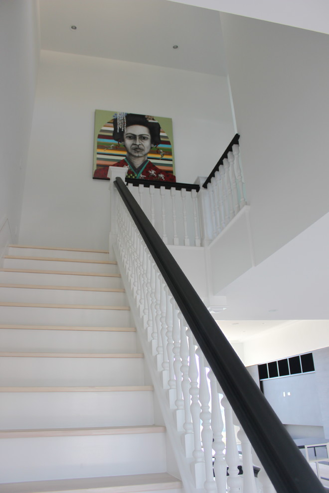 Пример оригинального дизайна: огромная п-образная деревянная лестница в стиле неоклассика (современная классика) с деревянными ступенями и деревянными перилами