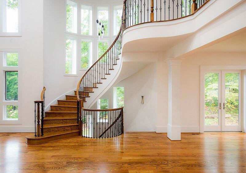 Large elegant wooden curved metal railing staircase photo in DC Metro with wooden risers