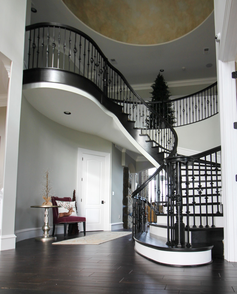 Example of a huge transitional wooden curved mixed material railing staircase design in DC Metro with wooden risers