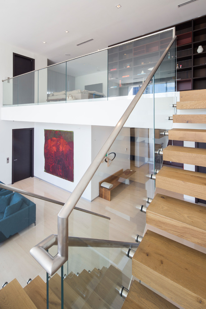 This is an example of a contemporary wood floating glass railing staircase in Miami with open risers.