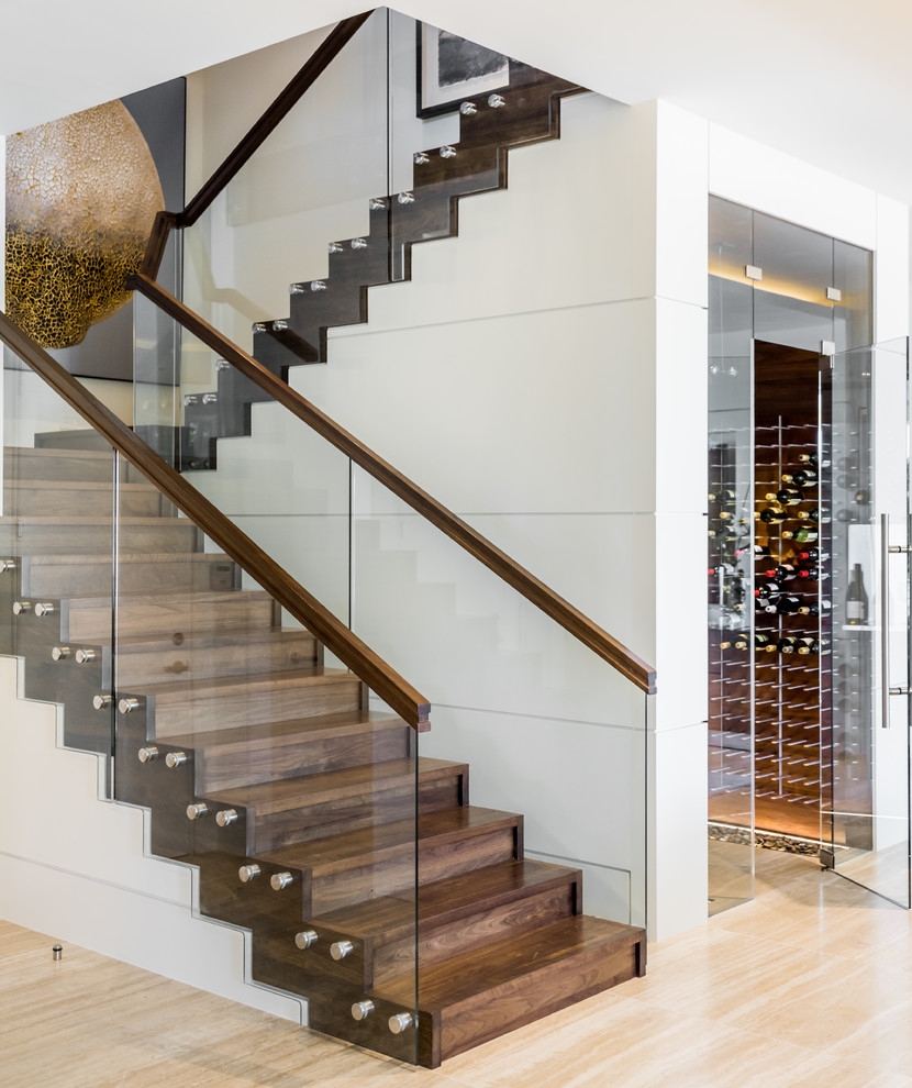 Inspiration for a coastal wood u-shaped glass railing staircase in Miami with wood risers and under stair storage.