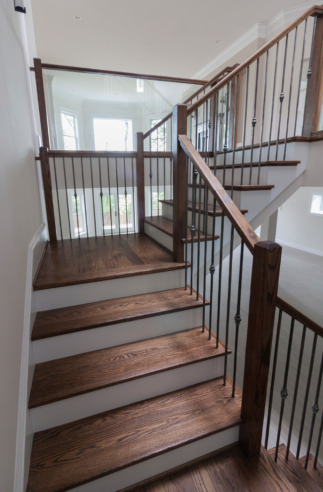 Стильный дизайн: огромная деревянная лестница на больцах в современном стиле с деревянными ступенями и стеклянными перилами - последний тренд