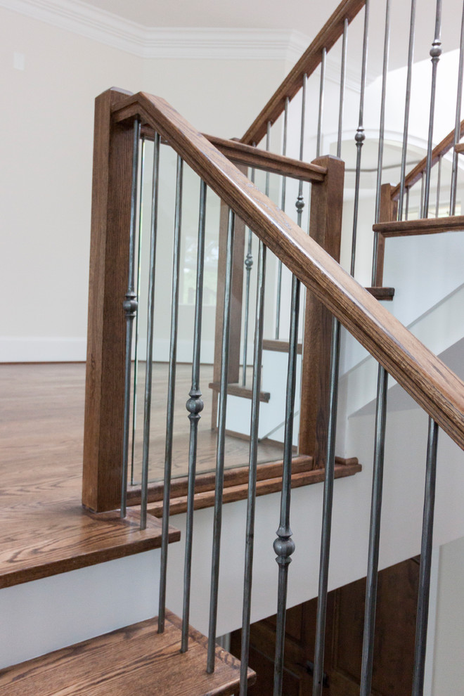 На фото: огромная деревянная лестница на больцах в современном стиле с деревянными ступенями и стеклянными перилами
