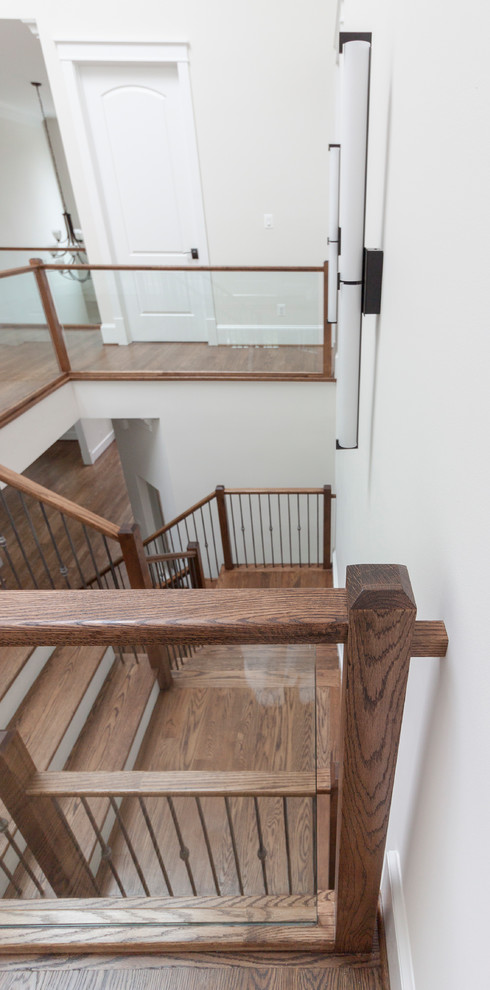 На фото: огромная деревянная лестница на больцах в современном стиле с деревянными ступенями и стеклянными перилами с