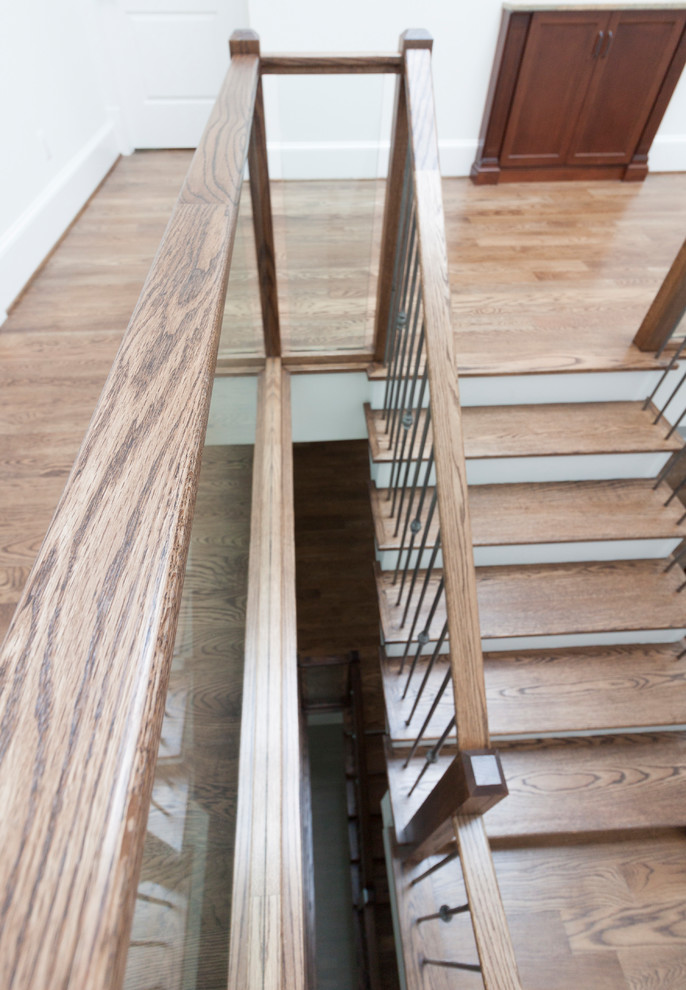 Пример оригинального дизайна: огромная деревянная лестница на больцах в современном стиле с деревянными ступенями и стеклянными перилами