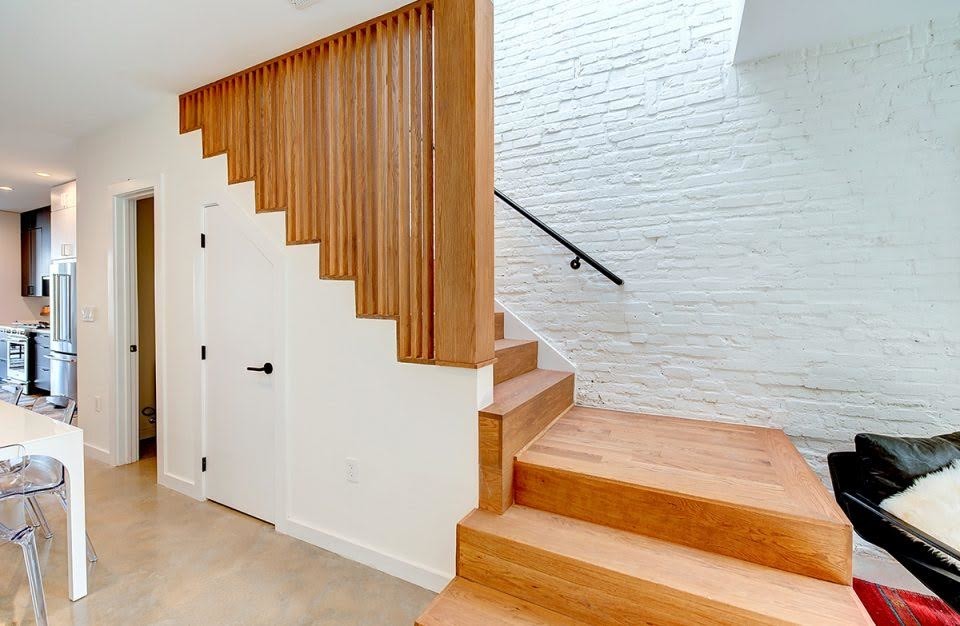 Cette image montre un grand escalier design en L avec des marches en bois, des contremarches en bois et un garde-corps en bois.