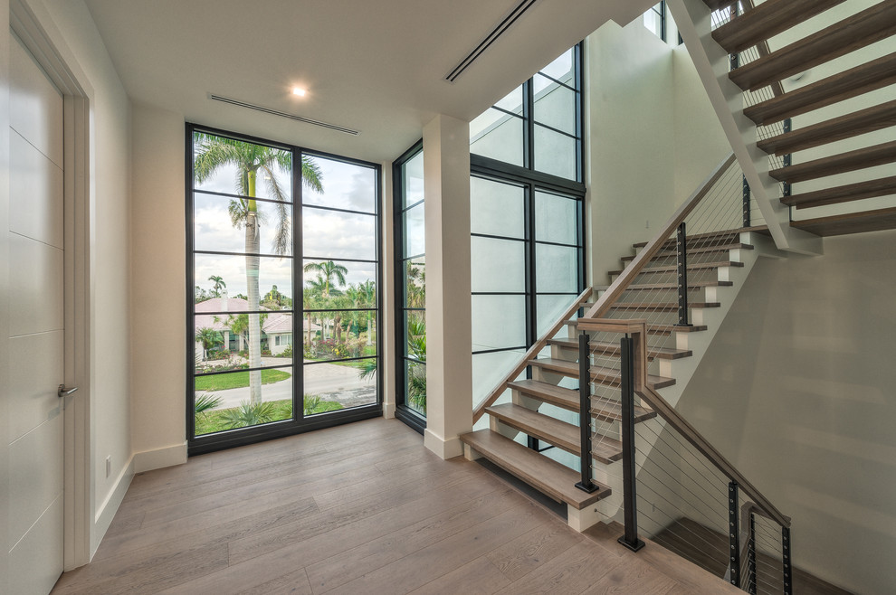 Photo of a large modern wood mixed railing staircase in Miami with wood risers.