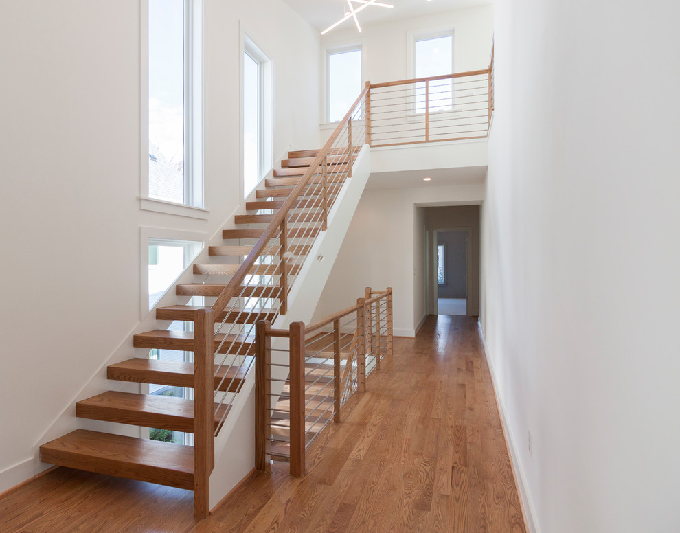Пример оригинального дизайна: большая лестница на больцах в современном стиле с деревянными ступенями и перилами из смешанных материалов
