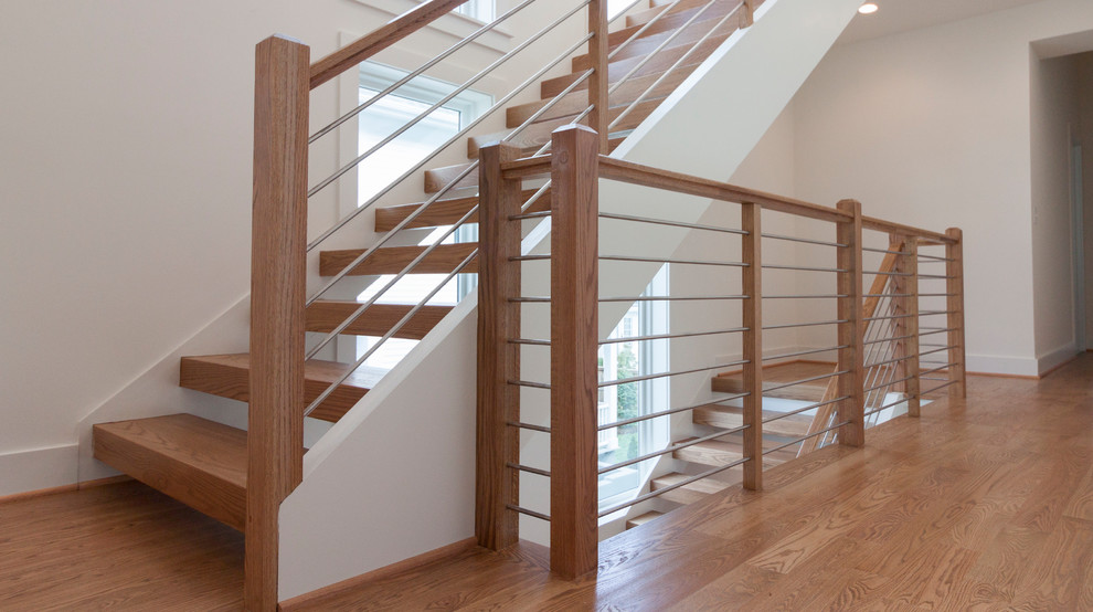 Réalisation d'un grand escalier flottant design avec des marches en bois et un garde-corps en matériaux mixtes.