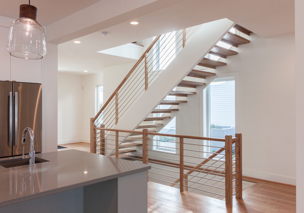 Idée de décoration pour un grand escalier flottant design avec des marches en bois et un garde-corps en matériaux mixtes.