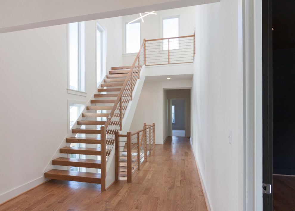 Exemple d'un grand escalier flottant tendance avec des marches en bois et un garde-corps en matériaux mixtes.