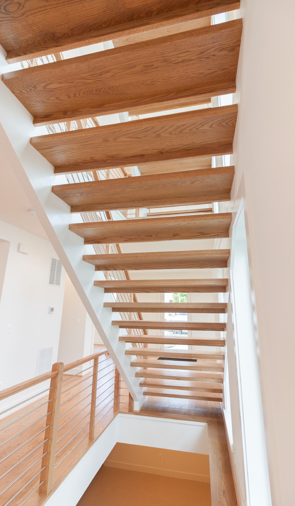 На фото: большая лестница на больцах в современном стиле с деревянными ступенями и перилами из смешанных материалов