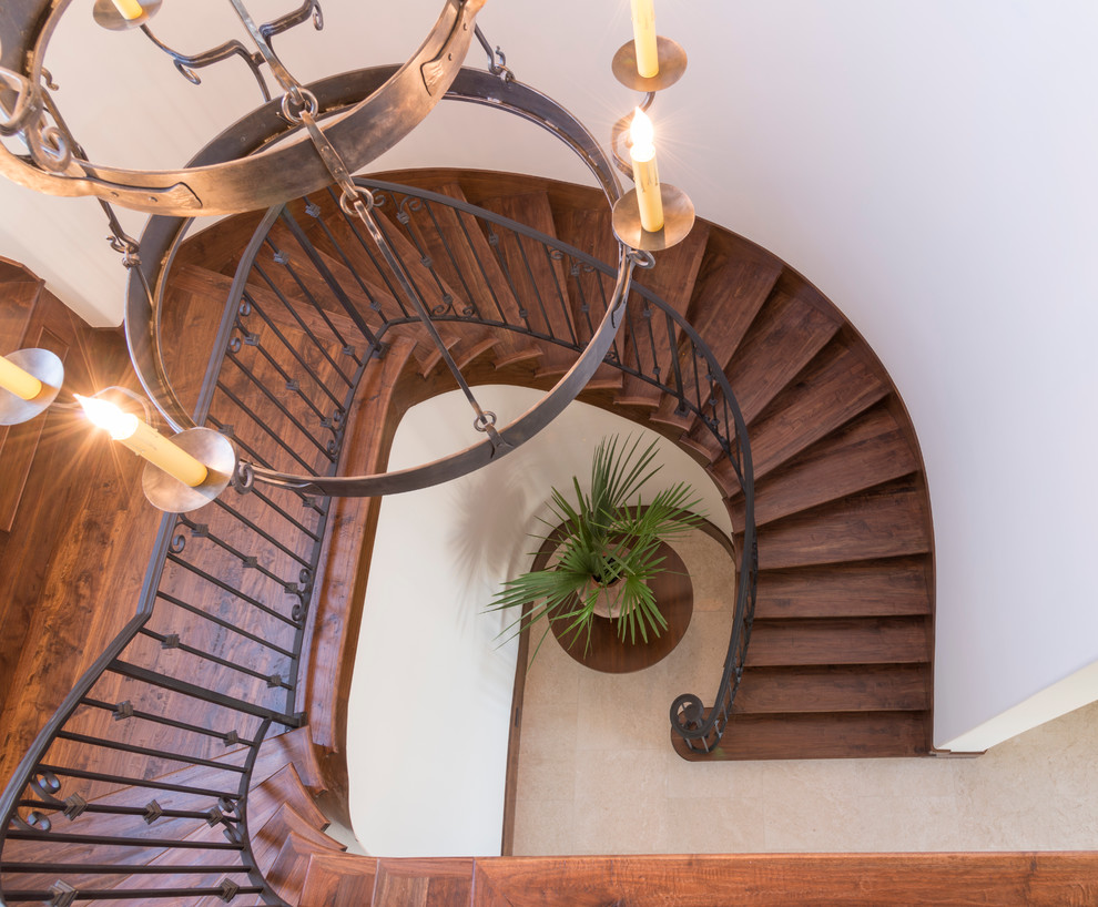 Источник вдохновения для домашнего уюта: большая изогнутая деревянная лестница в средиземноморском стиле с деревянными ступенями
