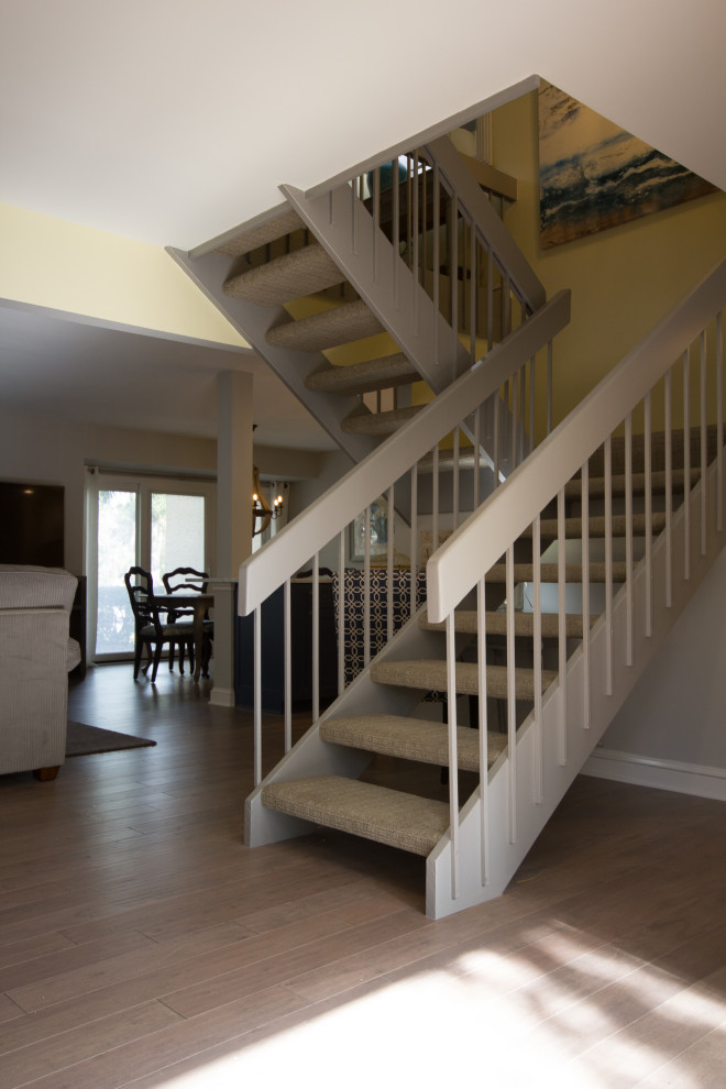Photo of a medium sized nautical carpeted floating metal railing staircase in Atlanta with open risers.