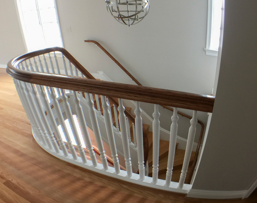Expansive classic wood u-shaped wood railing staircase in DC Metro with wood risers.
