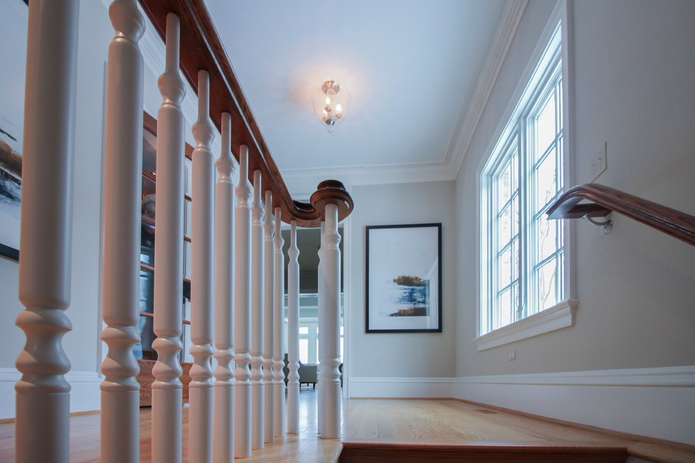 Expansive traditional wood u-shaped wood railing staircase in DC Metro with wood risers.