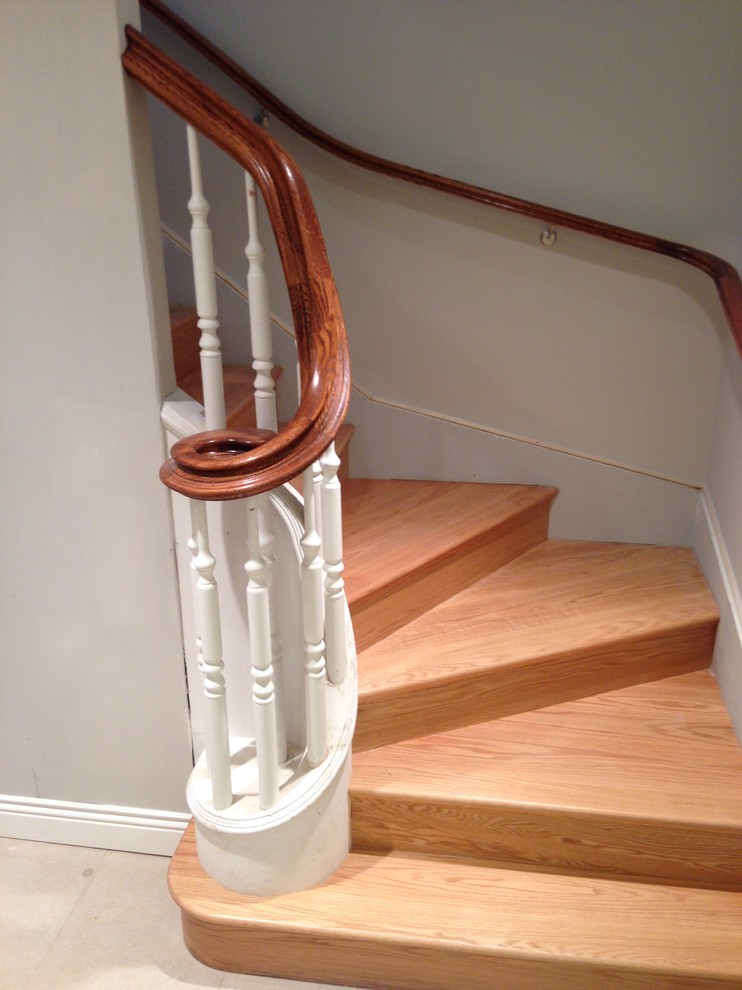 Expansive classic wood u-shaped wood railing staircase in DC Metro with wood risers.