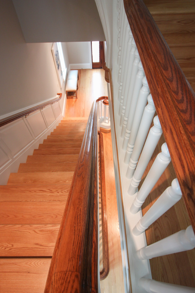 На фото: огромная п-образная деревянная лестница в классическом стиле с деревянными ступенями и деревянными перилами