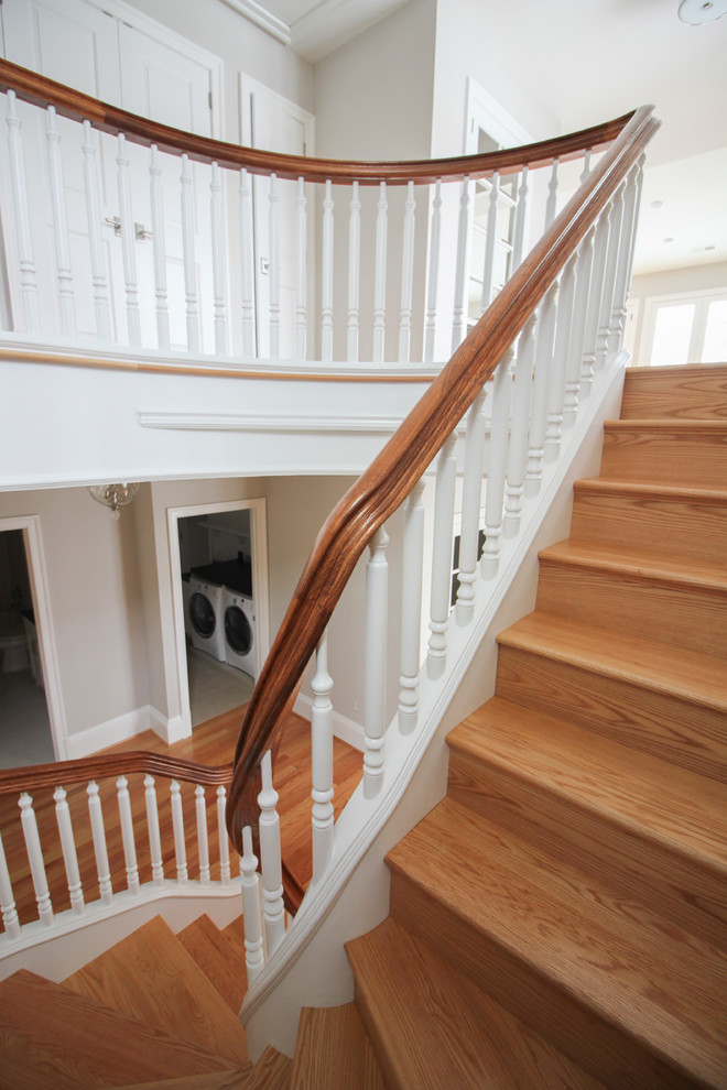 Idée de décoration pour un très grand escalier tradition en U avec des marches en bois, des contremarches en bois et un garde-corps en bois.