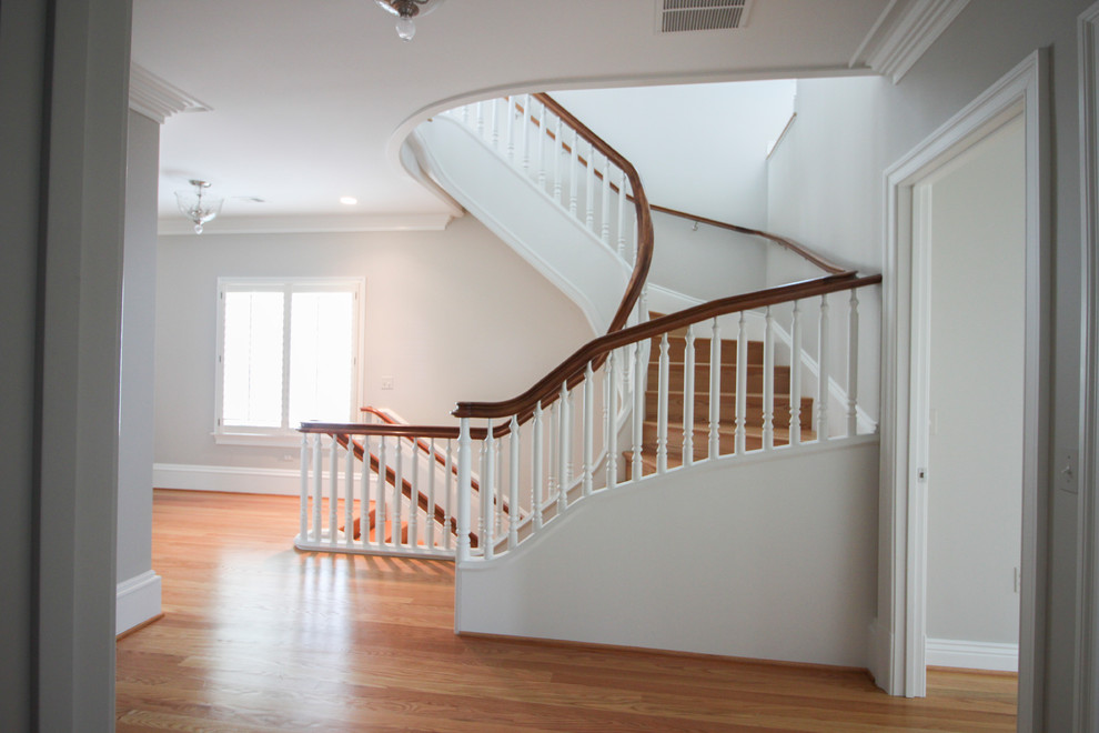 Пример оригинального дизайна: огромная п-образная деревянная лестница в классическом стиле с деревянными ступенями и деревянными перилами